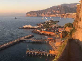 High angle view of sea by city against sky during sunset