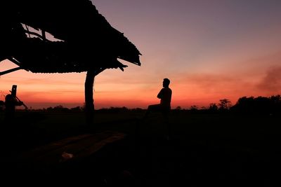 Silhouette people standing on field against sky during sunset