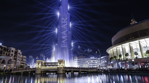 Illuminated bridge over river in city at night