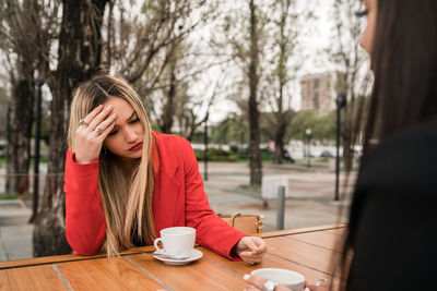 Young woman sitting by coffee cup on table