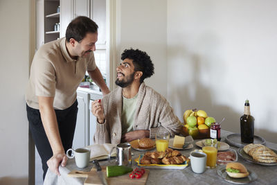 Happy gay couple eating breakfast at home