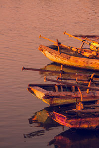 Boats moored on lake against sky during sunset