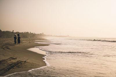 People on beach against clear sky