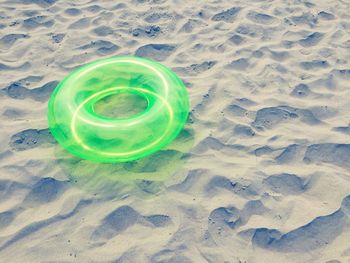 High angle view of green lifeguard ring on sand at beach