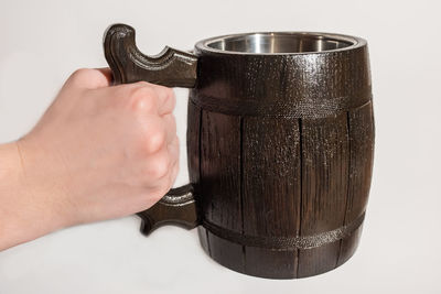 Close-up of hand holding metal against white background