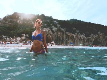 Woman standing in sea against sky