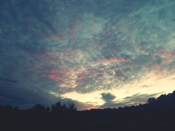 Low angle view of silhouette trees against cloudy sky