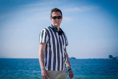 Portrait of young man standing at sea against sky