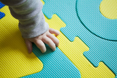 Cropped hand of baby on carpet