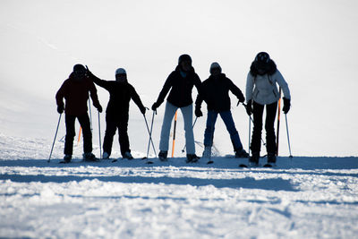 Rear view of friends skiing on snow covered landscape during winter