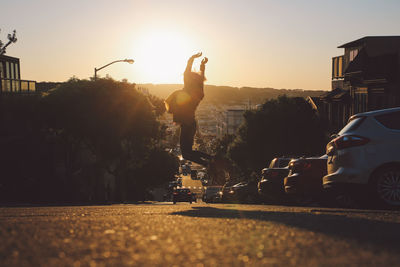 Man on street in city against sky during sunset