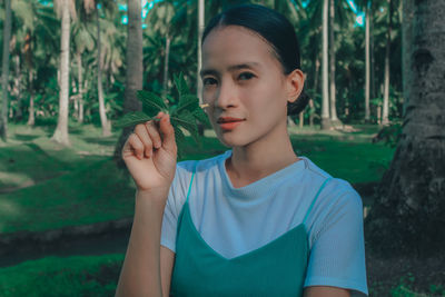 Portrait of young woman holding plant