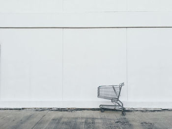 Close-up of shopping cart against white wall