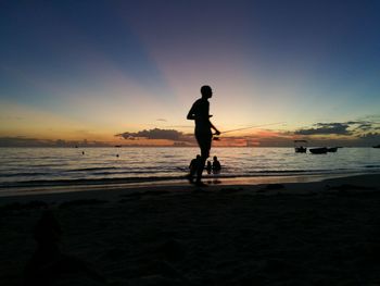 Silhouette man on beach against sky during sunset