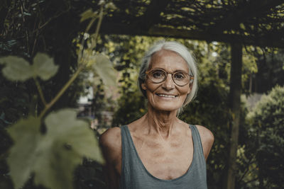 Portrait of young woman standing against trees