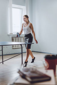 Full length of businesswoman playing tablet tennis in office