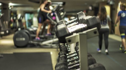 Dumbbells on rack with people in background at gym