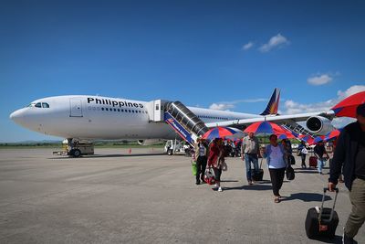 People on airport runway against sky