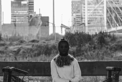 Young woman covering face while sitting on bridge