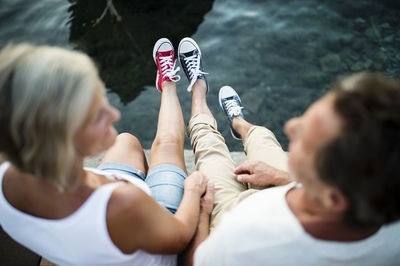 Senior couple sitting on jetty wearing sneakers