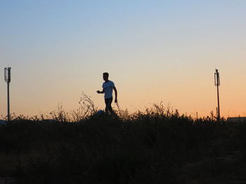 Man walking on field against sky during sunset