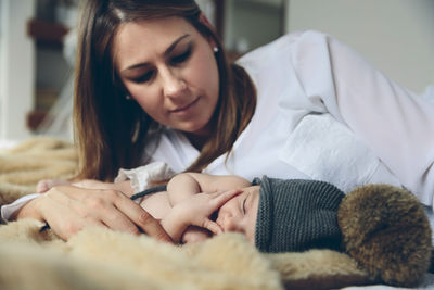 Mother looking at sleeping daughter on bed at home