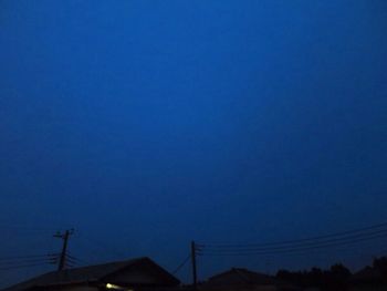 Low angle view of silhouette roof against blue sky