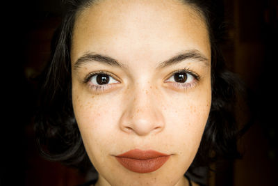 Close-up portrait of young woman against black background