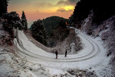 People walking on snow covered road against sky