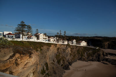 Scenic view of beach and buildings against clear blue sky
