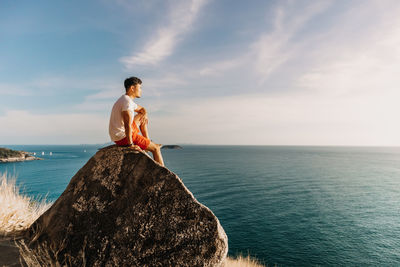 Rear view of shirtless man looking at sea against sky