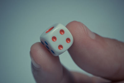 Cropped hand holding dice against gray background