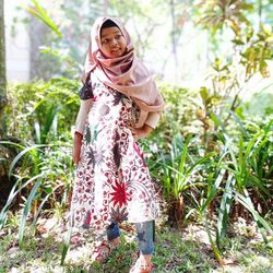 Portrait of young woman standing against plants