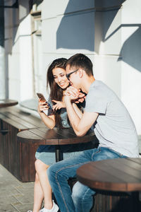 Smiling couple using mobile phone at outdoor cafe