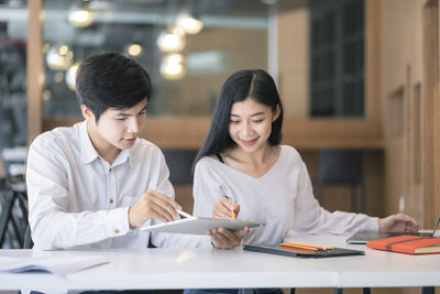 Business colleagues discussing over digital tablet at desk in office