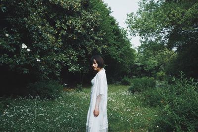 Woman standing by trees against plants