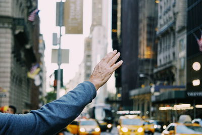 Cropped hand of man gesturing on city street