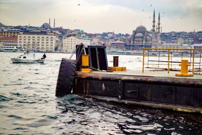 Tire at harbor by sea against blue mosque