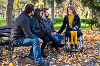 Young couple sitting on bench in park during autumn