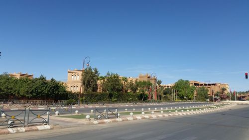 Street by buildings against clear blue sky