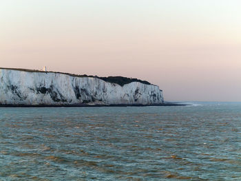 White cliffs by sea against clear sky