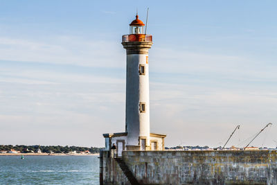 Lighthouse by sea against sky