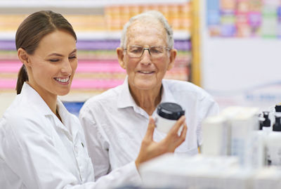 Smiling pharmacist assisting customer at store