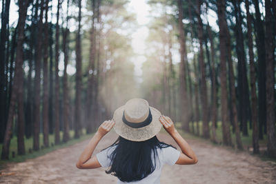 Rear view of woman standing in forest