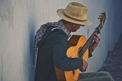 Man playing guitar by wall