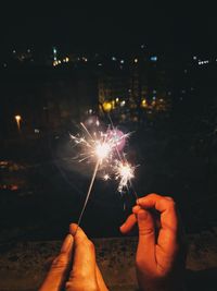 Person hand holding firework display at night