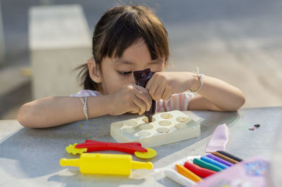 Close-up of cute girl playing with childs play clay at table outdoors