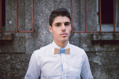 Portrait of smiling young man standing against window