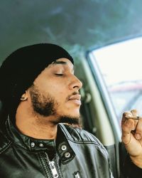 Close-up of young man smoking marijuana in car
