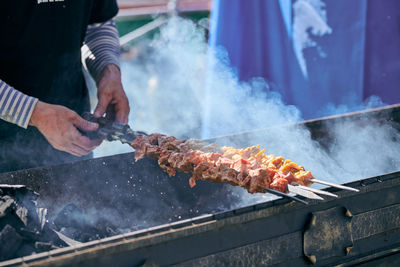 Midsection of man preparing food on barbecue grill